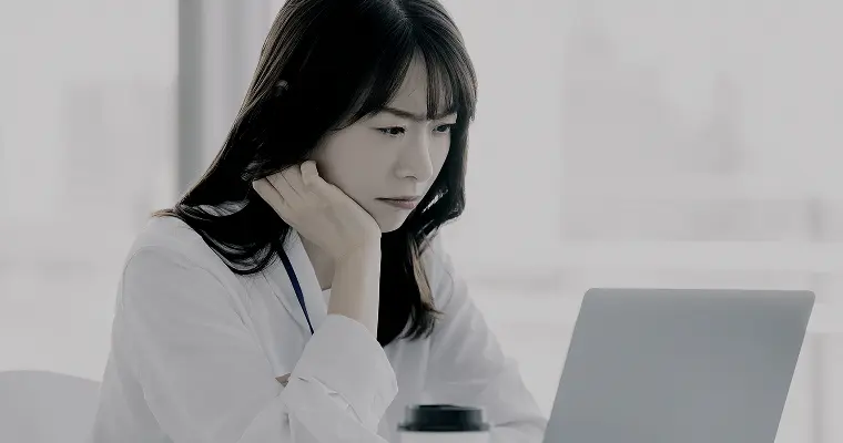 パソコンの前で悩んでいる女性の写真