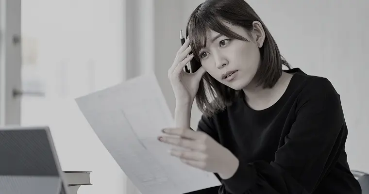 書類を見ながらで悩んでいる女性の写真